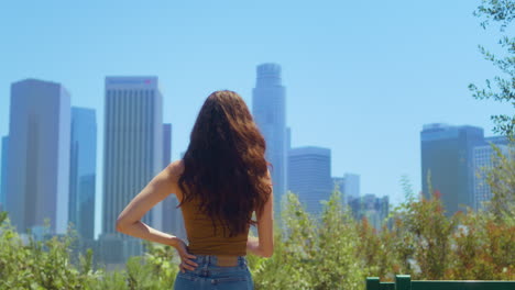 Woman-standing-back-in-park-enjoy-skyscrapers-view.-Girl-watch-blurred-cityscape