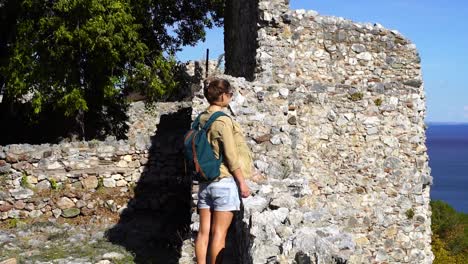 Woman-stands-on-a-wall-while-visiting-a-castle-on-a-stormy-day