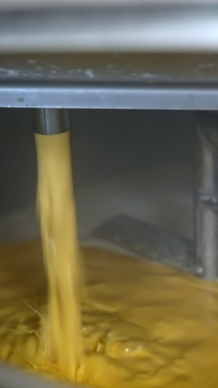 Yellow liquid pouring into container. Butter or cream production line. Food industry production. Dairy product manufacturer.. Vertical video