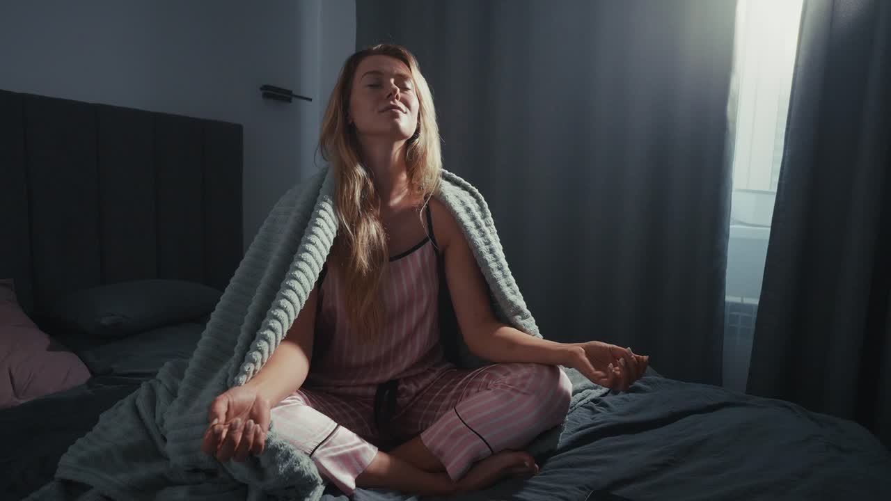 Woman meditating in bed in the morning