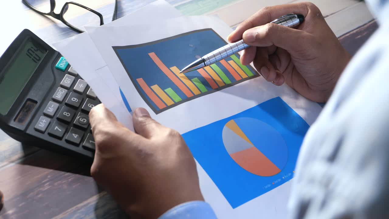 persona que analiza gráficos y gráficos con una calculadora