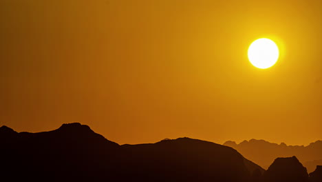 golden sunrise over the silhouette of rugged mountain terrain - time lapse