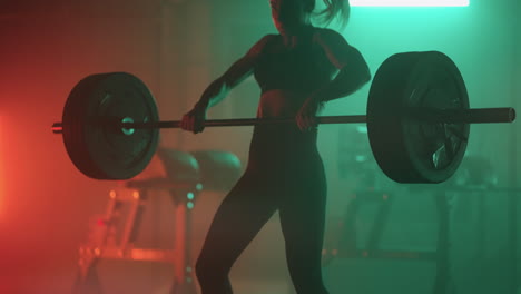 slow motion: athletic beautiful woman does overhead deadlift with a barbell in the gym. female professional bodybuilder workout weight lift exercises in the authentic sport training facility.