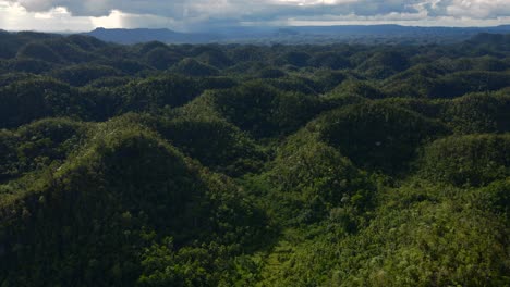 the chocolate hills in bohol, philippines, lush greenery under a cloudy sky, aerial view