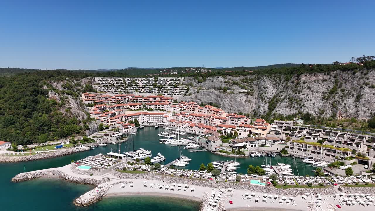 Un drone si allontana dal porticciolo di Portopiccolo, rivelando la spiaggia e il mare Adriatico