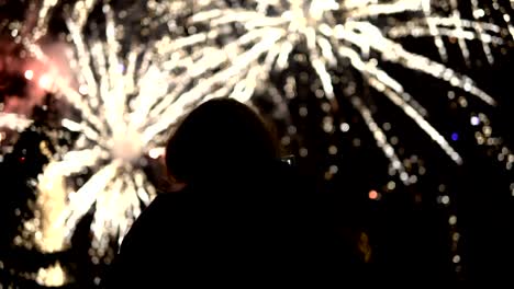 la niña toma fotos de fuegos artificiales en un teléfono móvil. silueta en el fondo del cielo iluminado por luces