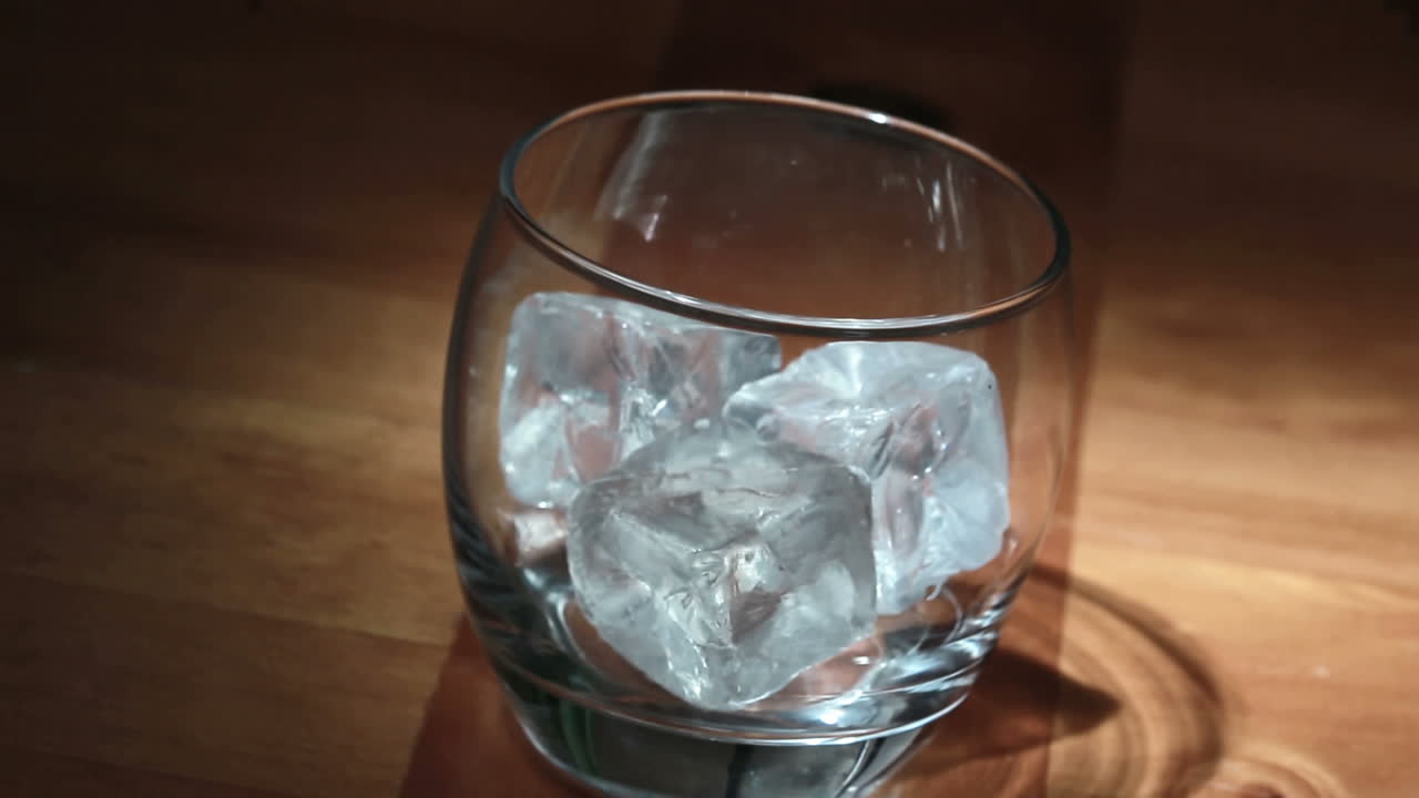 poniendo hielo a mano en el vaso y luego vertiendo whisky