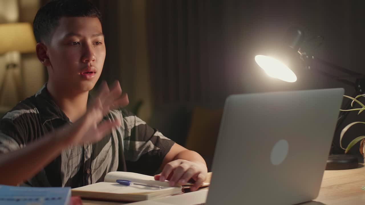 Teenage Boy Learning Online From Laptop, Raising Hand Distance Learning Online At Virtual Lesson Class With Teacher Tutor On Laptop By Video Conference