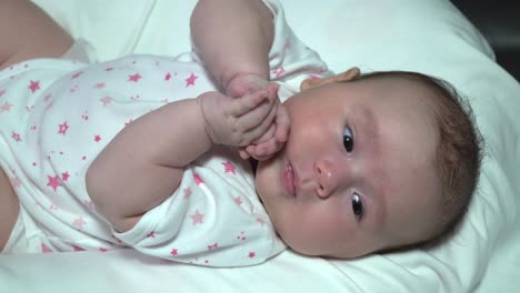 lado afuera de la niña recién nacida jugando con las manos en la cama