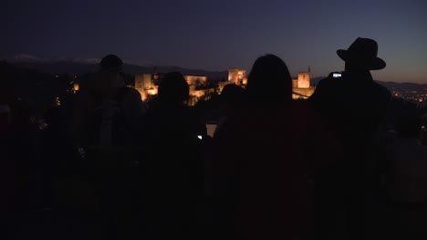 silueta de turistas tomando fotos de la alhambra después de la puesta de sol