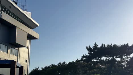 early morning light on an airport control tower surrounded by trees, clear blue sky backdrop