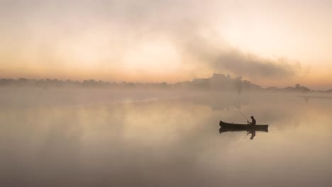 aerial apporaching a man fishing in a lake in the early morning hours all by himself at imire, zimbabwe