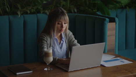 Young Asian attractive female office worker sitting at the laptop computer at the desk working and thinking.