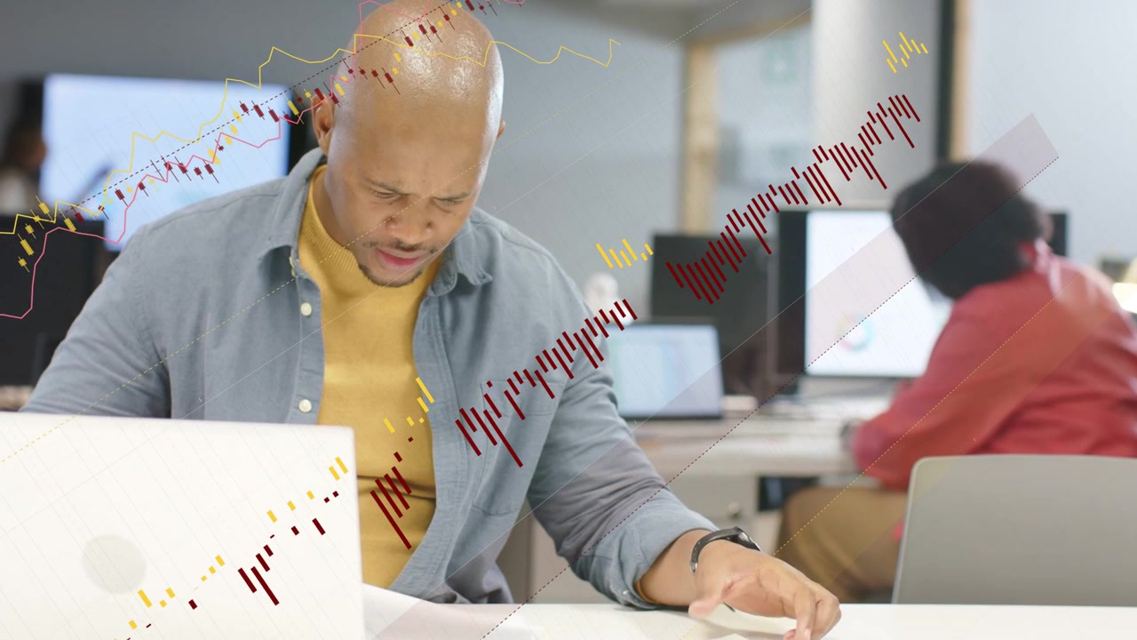 Man reacting to new laptop data, lifting printout, consulting coworker with animated finance charts