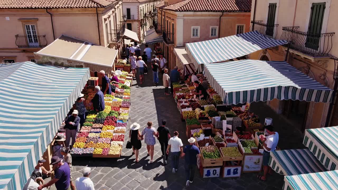 Aerial view of a vibrant outdoor market with striped tents and colorful produce