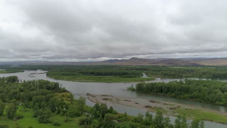 aerial view of a river flowing through a green valley with mountains in the background