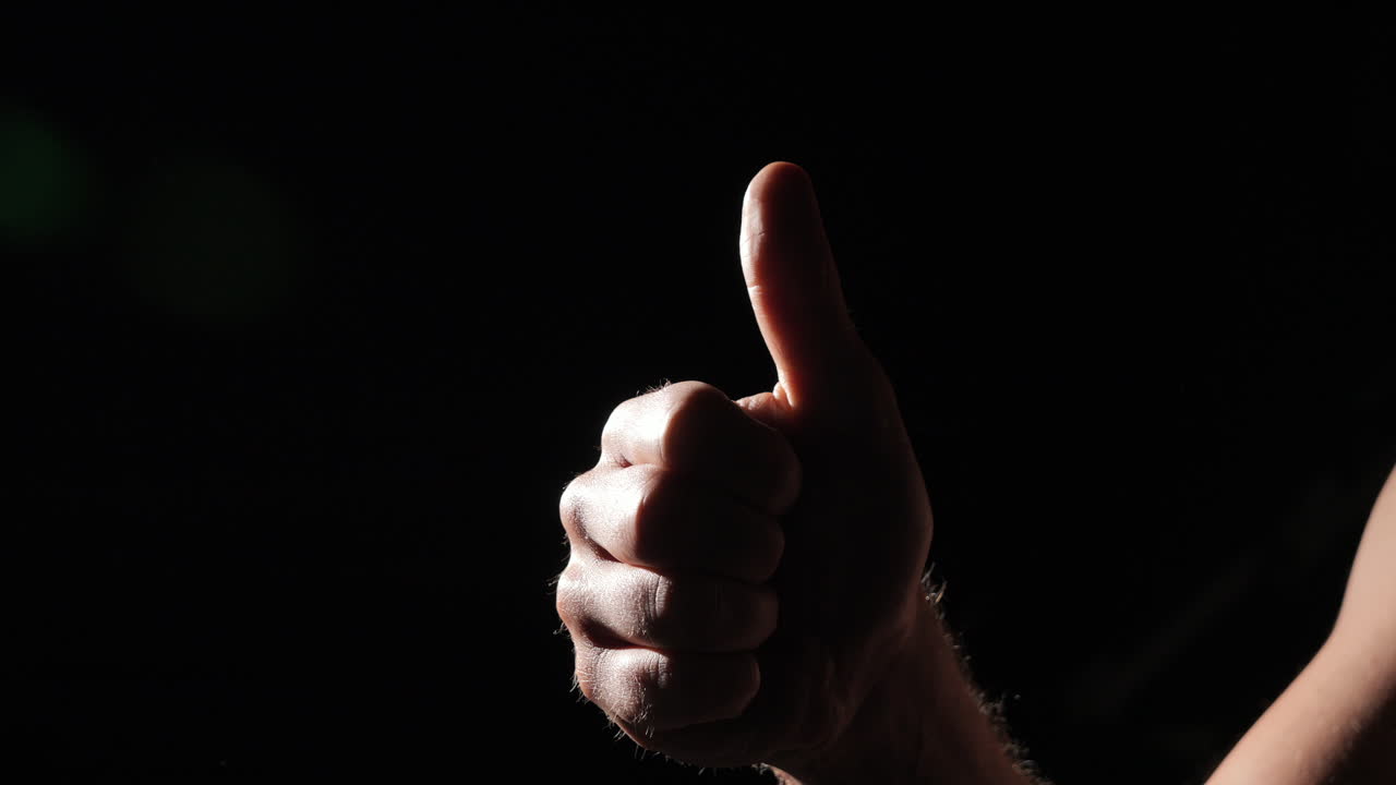 de cerca de los pulgares de la mano iluminados sobre un fondo negro