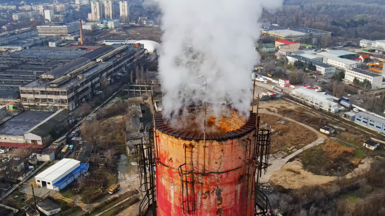 Aerial drone view of Chisinau. Tube of the thermal station with smoke coming out. Industrial zone near it and cityscape on the background. Cloudy weather. Moldova