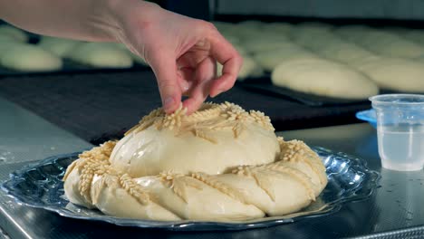 a worker wets pie decorations for a pie before adding them.