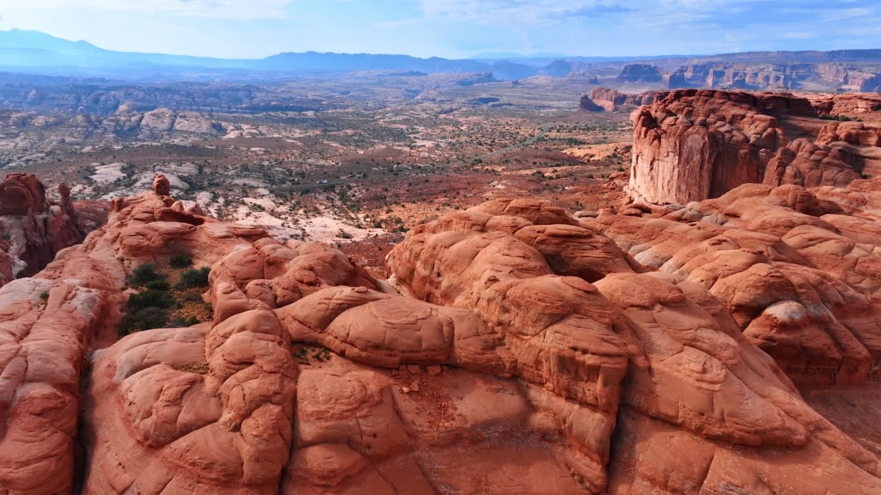 Avvicinamento alle rocce arrotondate e arancioni nell'Arches National Park nello Utah, USA. Un camper percorre l'autostrada sullo sfondo. Vista aerea