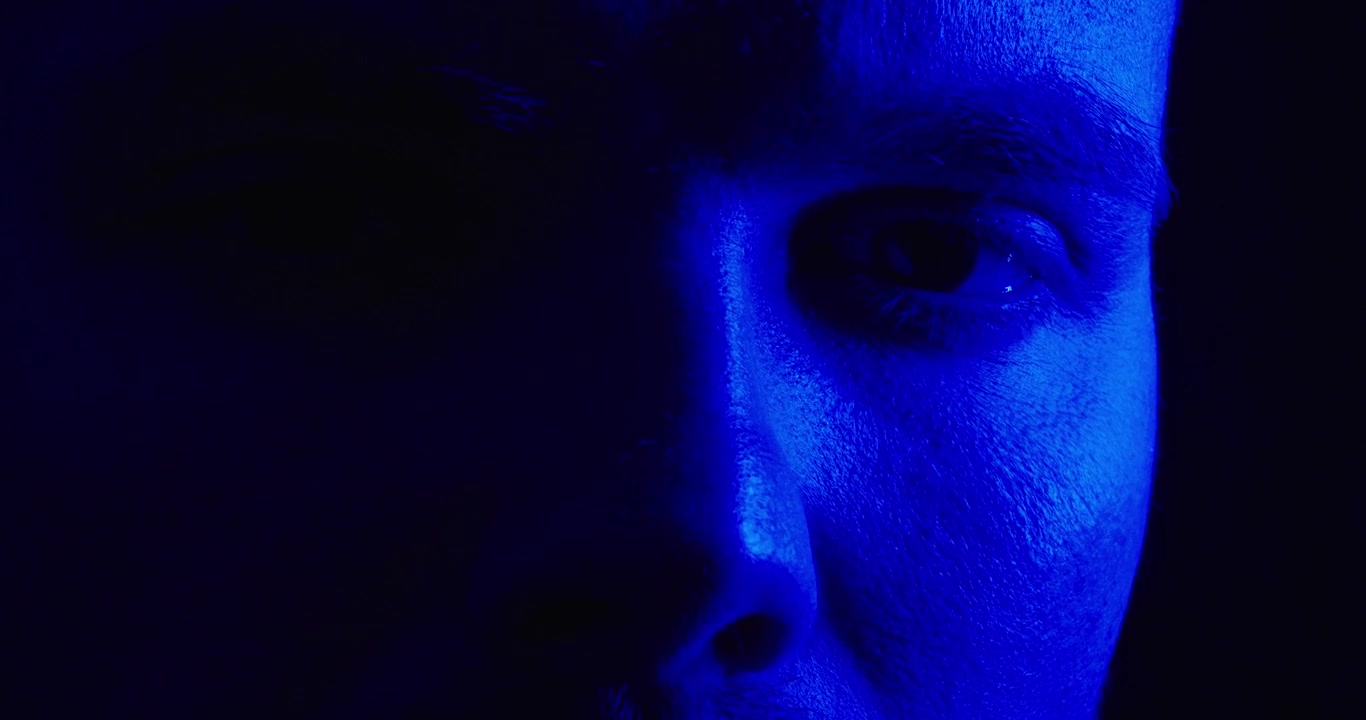 Primo piano del volto di una persona illuminato dalla luce rossa lampeggiante di una sirena della polizia su uno sfondo scuro. Concetto drammatico di crimine, emergenza, indagine e suspense.