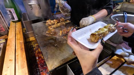 vendor hands over cooked skewers to customer