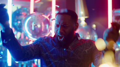 Playful-afro-man-having-fun-in-club.-African-guy-celebrating-on-neon-background