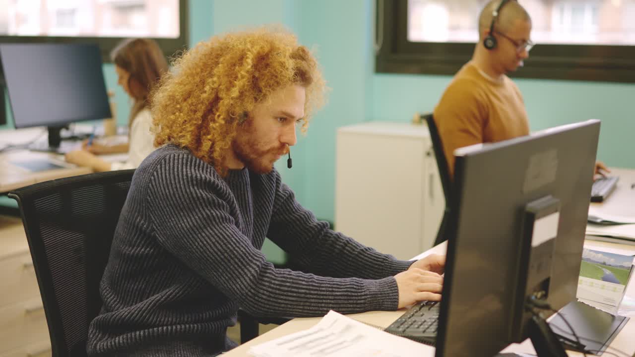 Modern man working in a coworking using computer and headset