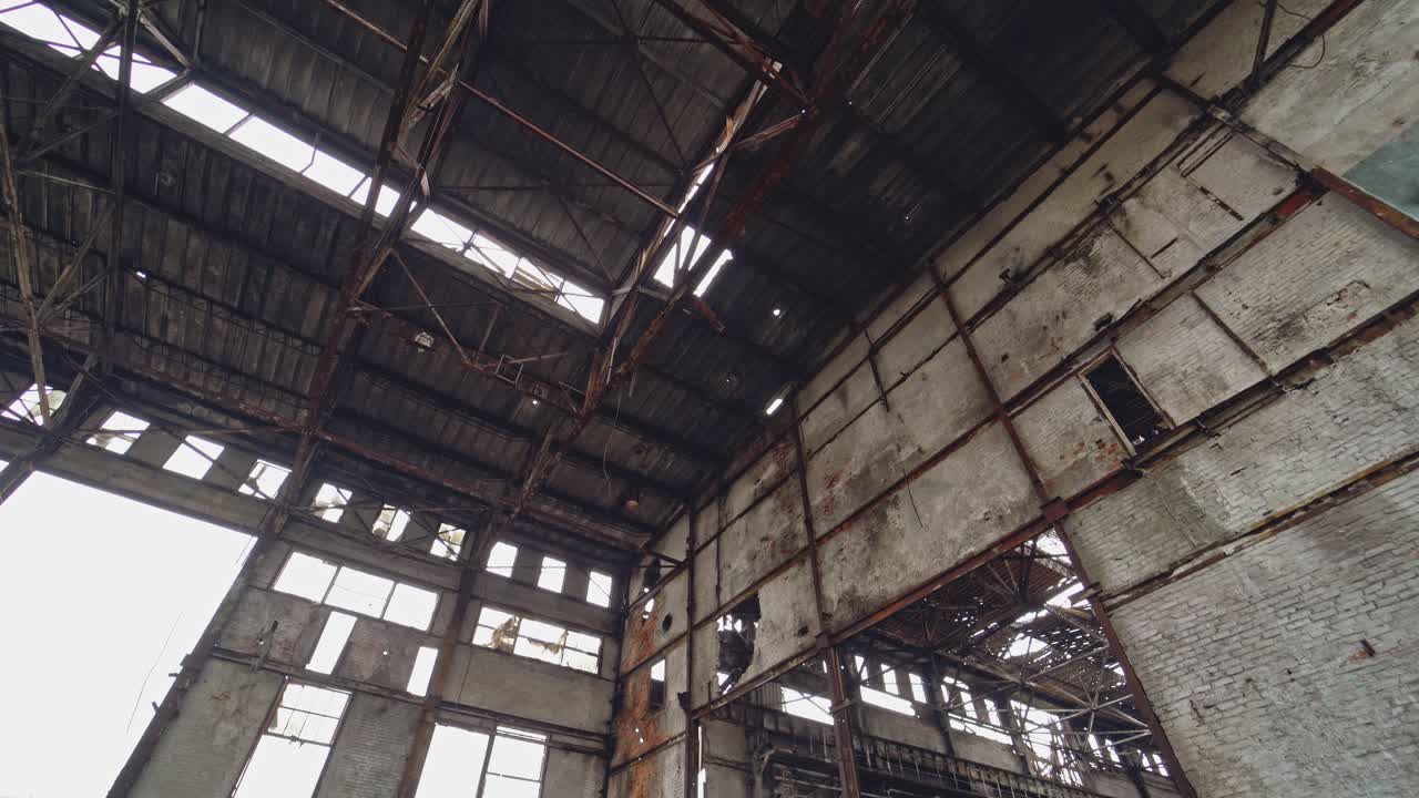 Pile of used tires of car are on the ground inside an abandoned factory on the background of the old gray walls. Camera motion from down to up.