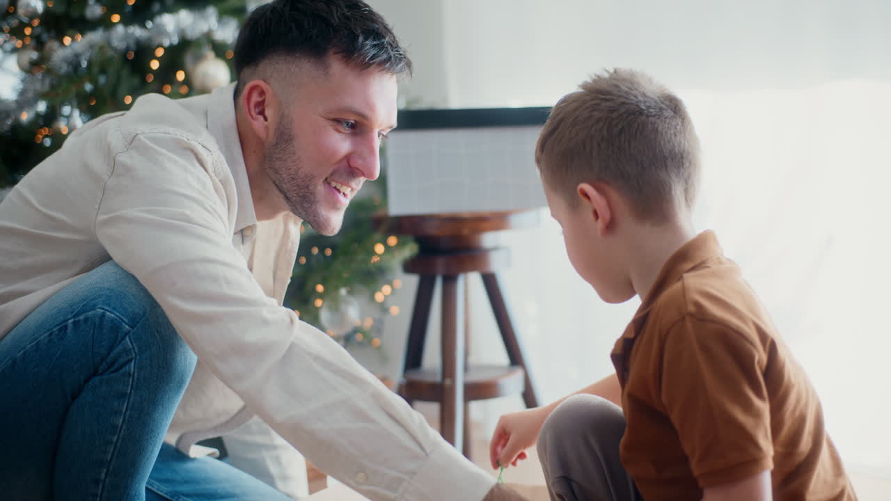 papá y hijo cuelgan bolas de navidad en el árbol de navidad
