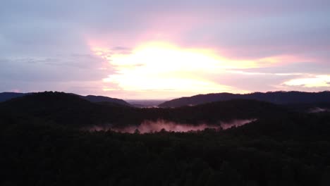 puesta de sol rosa en las montañas humeantes con nubes bajas en la distancia