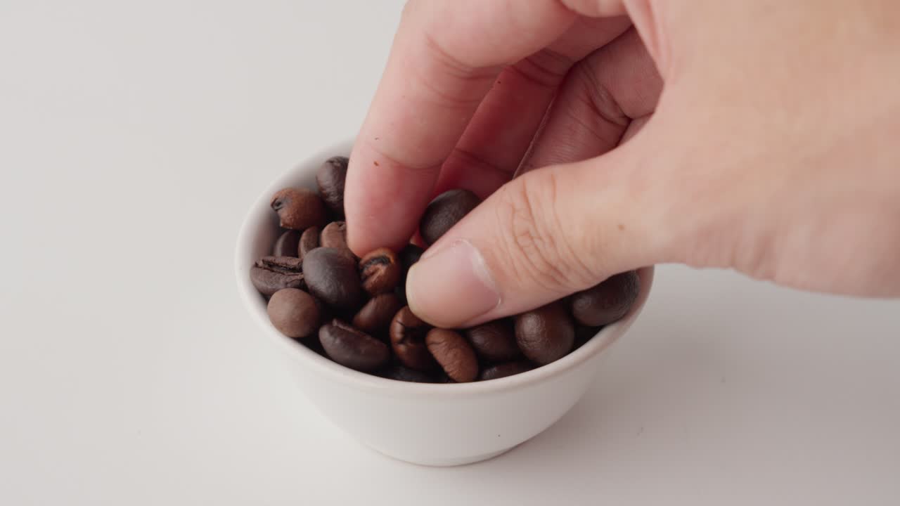 Roasted coffee beans being touched by a hand to test their texture