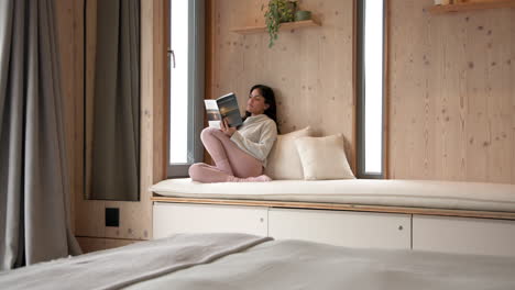 relaxing at home, woman reading book on cozy window seat, copy space