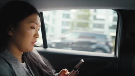 business chinese woman driving in a taxi and making a phone call