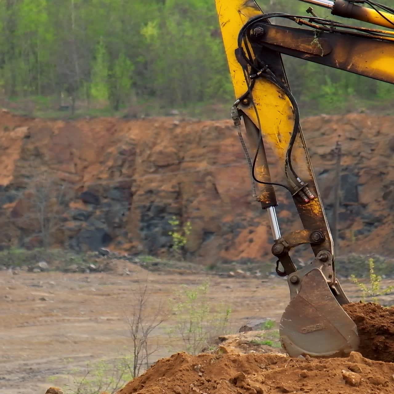 Excavator bucket digs up soil. Excavator iron bucket scoops up the ground. Excavator shovel digging on nature background. Slow motion.