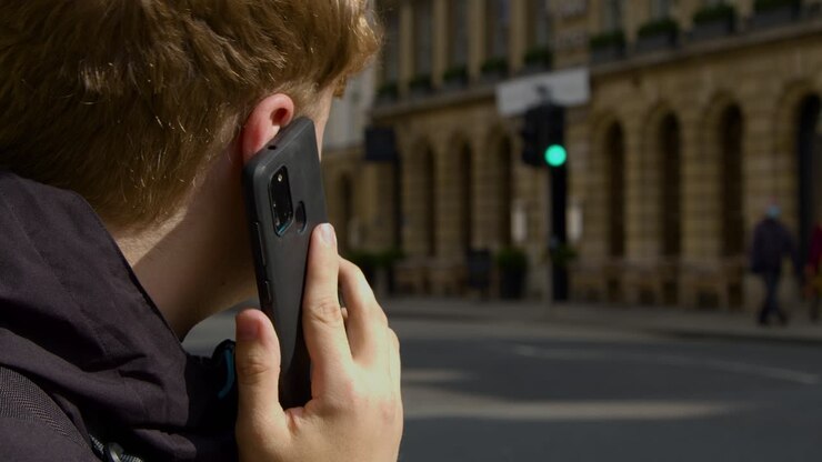 Ripresa da dietro la spalla di un uomo che parla al cellulare in una strada affollata