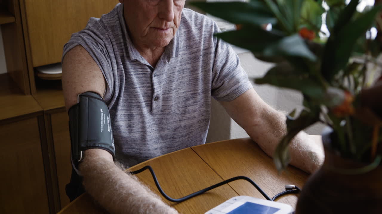 Elderly man measuring his blood pressure at home