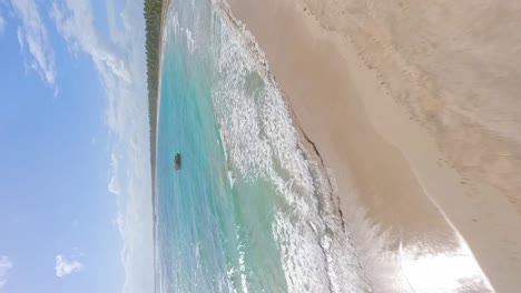 Tiro-Vertical-De-Playa-Los-Coquitos-Con-Barco-De-Pesca-En-El-Agua-Turquesa-En-República-Dominicana---Fpv-Aéreo