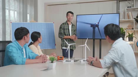 태양전지를 가진 아시아 남성 엔지니어가 사무실에서 풍력 터빈에 대한 발표를 성공시켰고, 관객들은 박수를 치며 인상적이라고 느습니다.