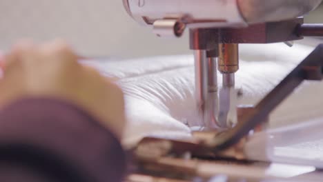 close-up of a sewing machine needle working on a boxspring mattress in a bed factory