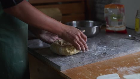 mezcla de masa cruda amassada a mano en una mesa de mármol, filmada como una toma de cámara lenta de primer plano medio
