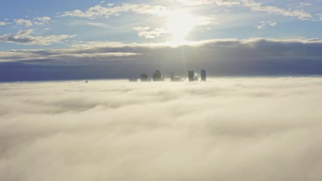 dolly back aerial shot over morning fog clouds from canary wharf skyscrapers sunrise