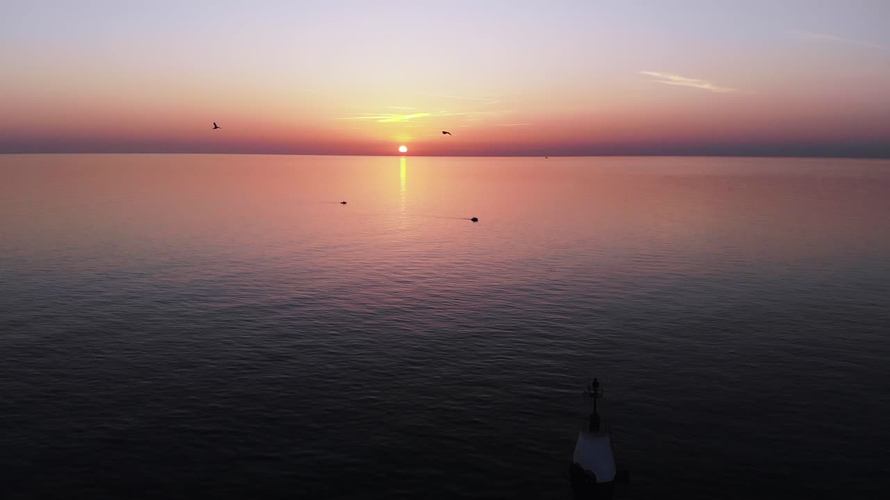 항해 마커 위로 날아가는 갈매기 떼와 석양에 끝없는 잔잔한 열대 바다