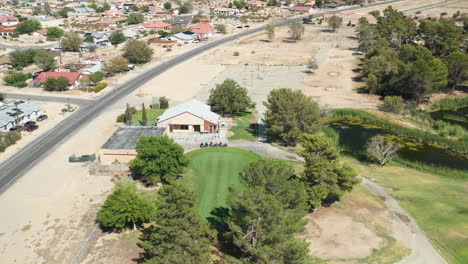 Un-Campo-De-Golf-Verde-En-Una-Comunidad-Desértica---Vista-Aérea-En-órbita-Inclinada-Hacia-Abajo