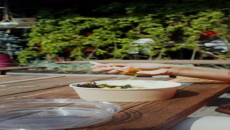 woman eating takeout bowl outdoors