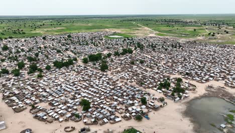 static high-angle shot of makeshift nigerian refugee town with oasis near meadow