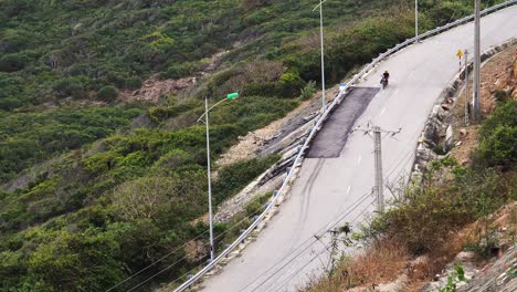 un joven conduce por una vieja carretera rural vietnamita con una tabla de surf amarilla adjunta