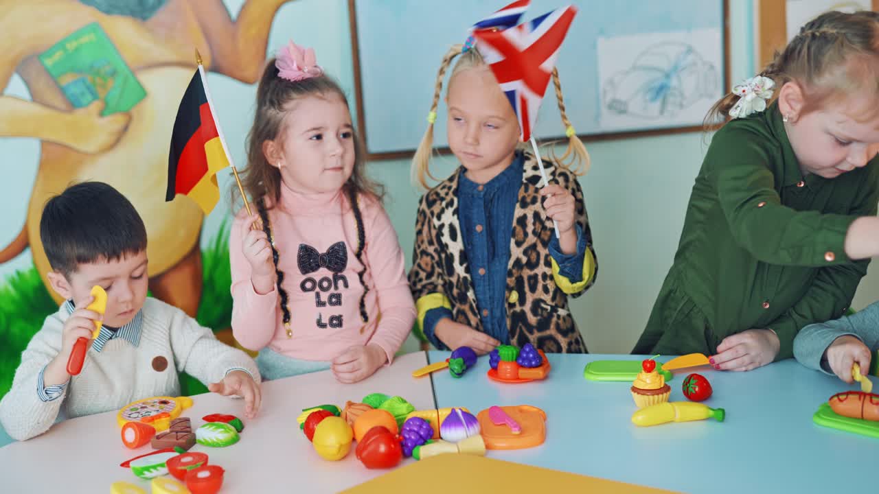Little girls with English and German flags. Children in the classroom. Two curious girls holding flags and waving them on the background of educational center.