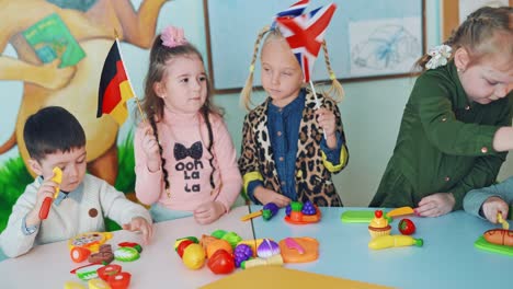 little girls with english and german flags. children in the classroom. two curious girls holding flags and waving them on the background of educational center.