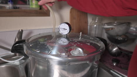 spraying tap water on stainless lid of a pressure canner to quickly remove pressure, close up